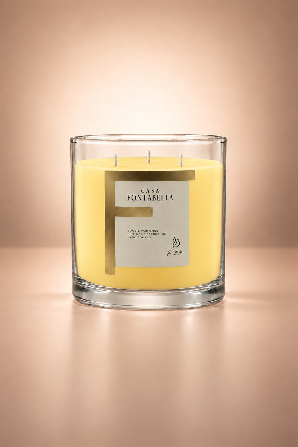 Vela aromática de Casa Fontabella en frasco Mónaco transparente con cera en tono amarillo, encendida — cera de soya y coco con tres mechas de algodón.