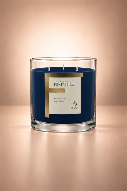 Vela aromática de Casa Fontabella en frasco Mónaco transparente con cera en tono azul rey, encendida — cera de soya y coco con tres mechas de algodón.
