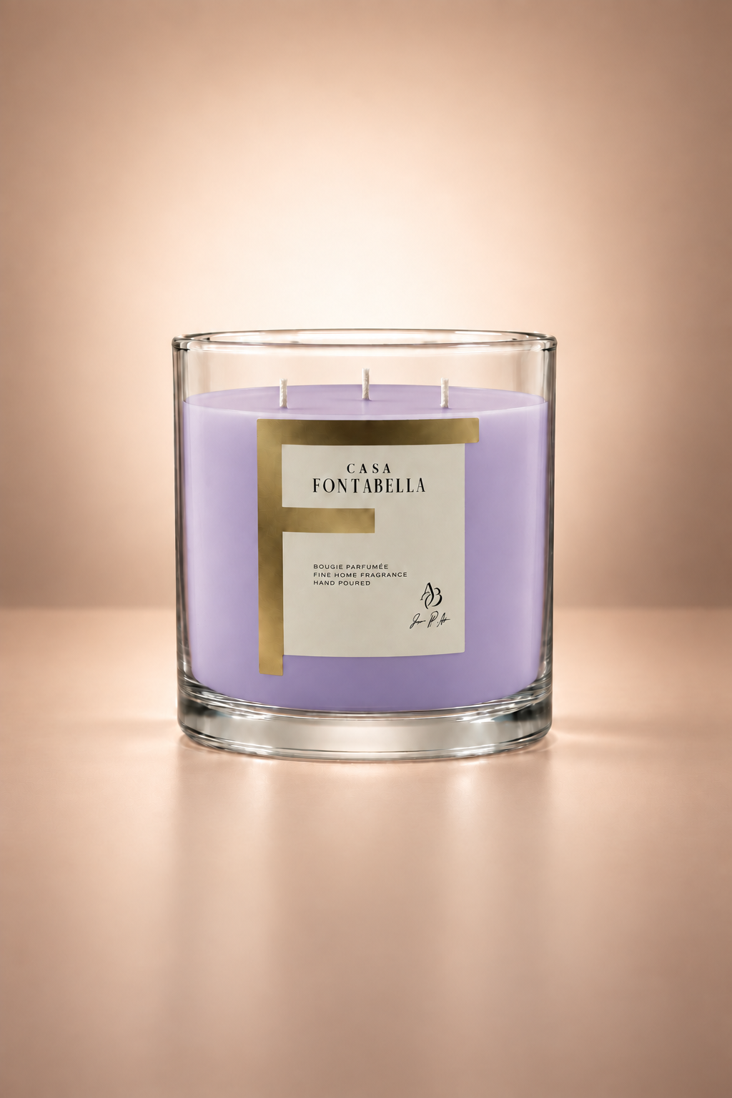 Vela aromática de Casa Fontabella en frasco Mónaco transparente con cera en tono lavanda, encendida — cera de soya y coco con tres mechas de algodón.