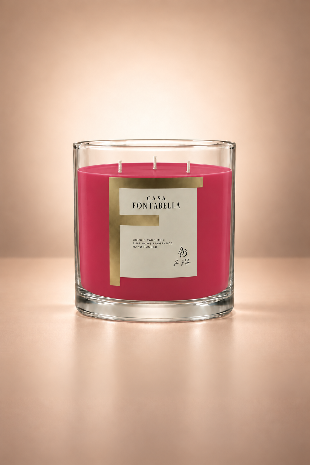 Vela aromática de Casa Fontabella en frasco Mónaco transparente con cera en tono magenta, encendida — cera de soya y coco con tres mechas de algodón.