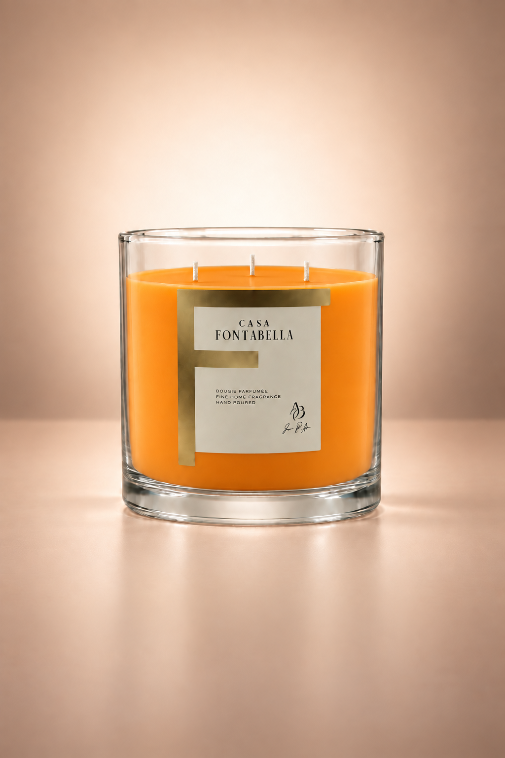 Vela aromática de Casa Fontabella en frasco Mónaco transparente con cera en tono naranja, encendida — cera de soya y coco con tres mechas de algodón.