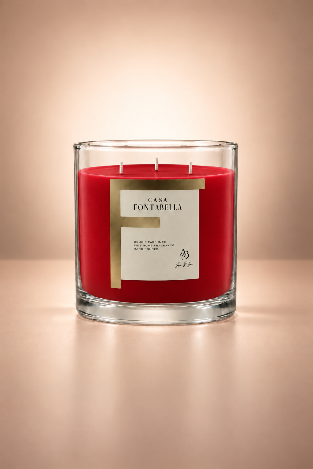 Vela aromática de Casa Fontabella en frasco Mónaco transparente con cera en tono rojo, encendida — cera de soya y coco con tres mechas de algodón.