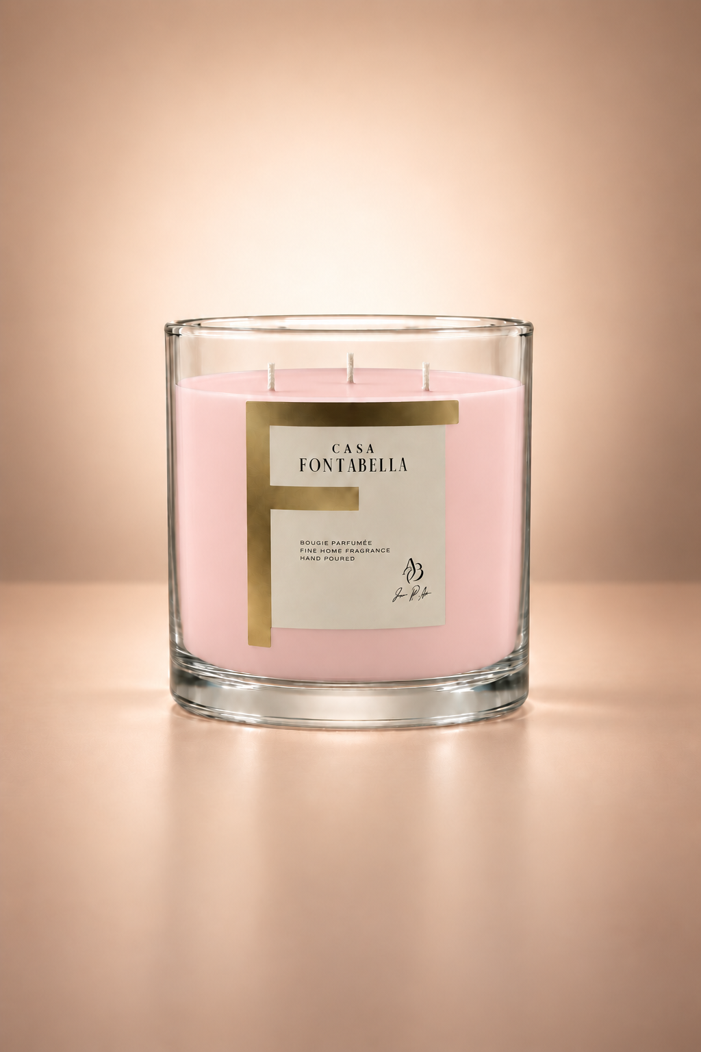 Vela aromática de Casa Fontabella en frasco Mónaco transparente con cera en tono rosa pálido, encendida — cera de soya y coco con tres mechas de algodón.