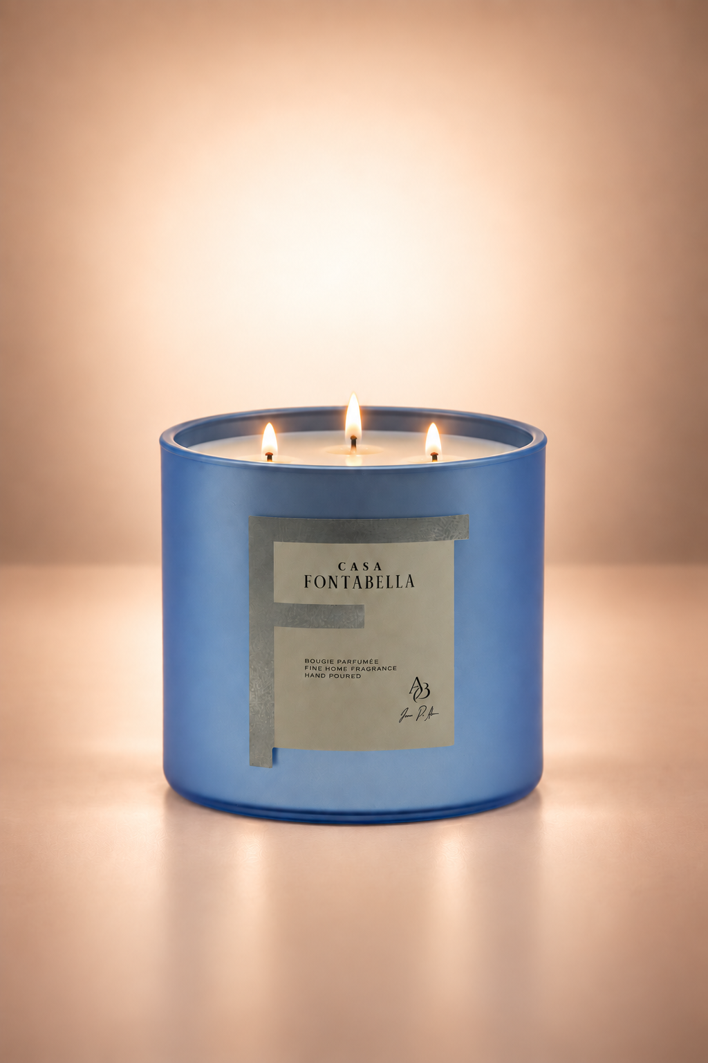 Vela aromática de Casa Fontabella en frasco Mónaco azul claro mate metálico, encendida — cera de soya y coco con tres mechas de algodón.