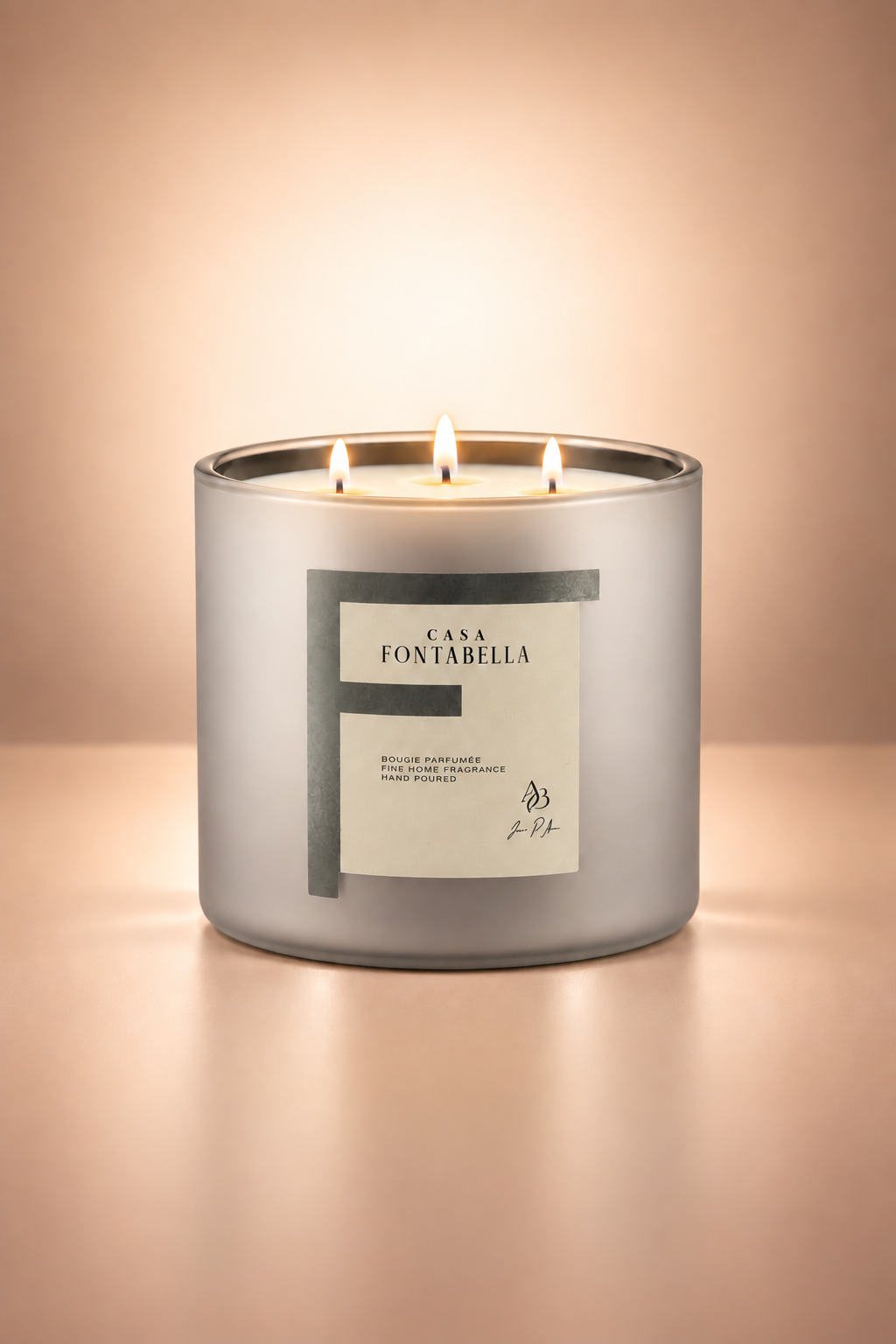 Vela aromática de Casa Fontabella en frasco Mónaco plata mate metálico, encendida — cera de soya y coco con tres mechas de algodón.